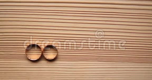 木制背景上的金色结婚戒指视频的预览图