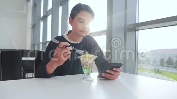 机场等待飞机航班十几岁的女孩吃沙拉看上去像智能手机在咖啡馆里上网机场生活方式视频的预览图