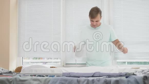 年轻人站在船后用热气腾腾的熨斗在做家务时熨衬衫4k慢镜头视频的预览图