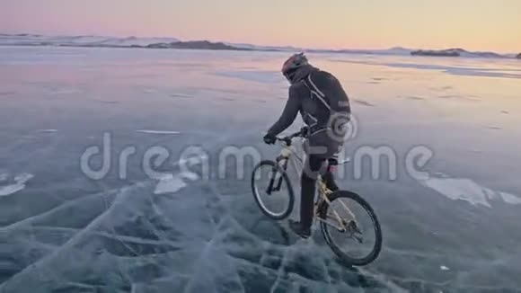 人在冰上骑自行车骑自行车的人穿着灰色的羽绒服背包和头盔冰冻的冰视频的预览图