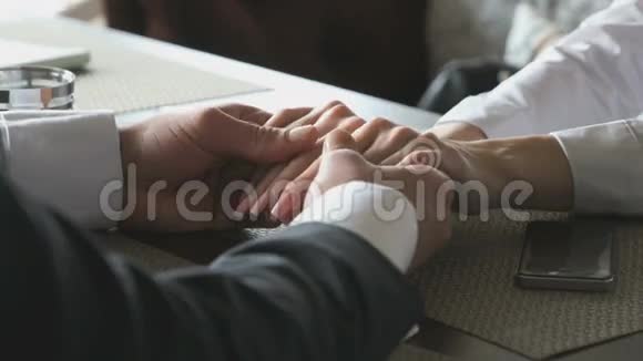 年轻夫妇手牵手坐在桌子上视频的预览图