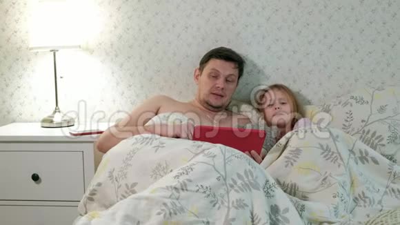 爸爸和小女儿在床上玩平板电脑视频的预览图