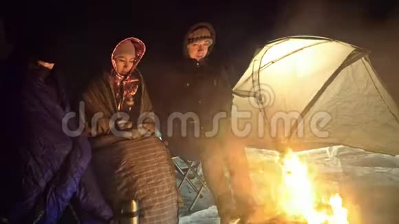 夜间有三个乘火的旅行者在冰上在冰上露营帐篷就在火旁边贝加尔湖就在附近视频的预览图