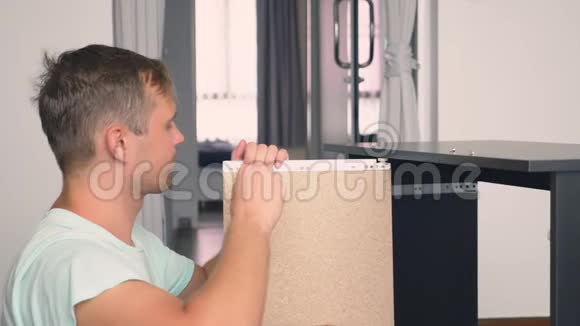 一个年轻人在他家的客厅里独立收集家具一个男人收集一张电脑桌视频的预览图