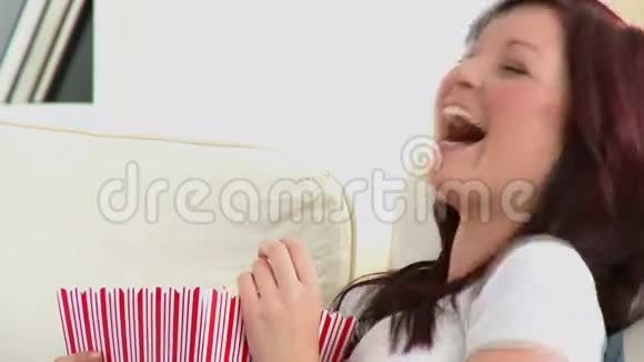 笑着在沙发上吃爆米花的白种人女人视频的预览图