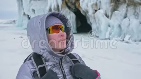 贝加尔湖冰上女子旅行去冬岛旅行女孩走在冰岩脚下旅行者看着视频的预览图