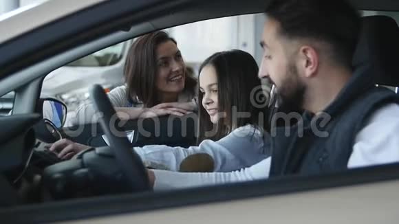 幸福的年轻一家坐在一辆新车上的经销商视频的预览图