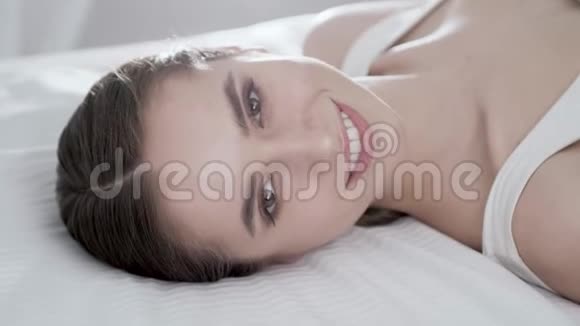 面部护理躺在床上摸脸的年轻女子视频的预览图