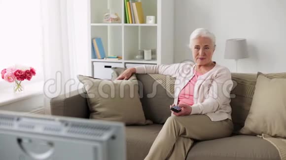 快乐的老年妇女在家看电视视频的预览图