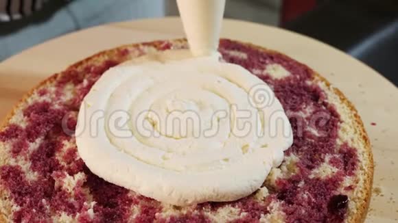 在海绵蛋糕上涂上奶油的特写旋转台上的蛋糕视频的预览图