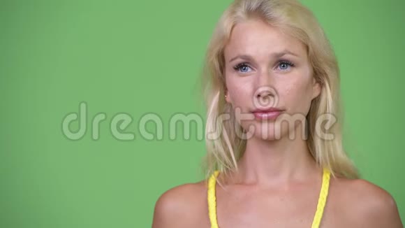 年轻漂亮的金发女郎在绿色背景下思考视频的预览图