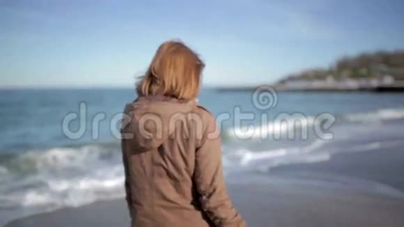 美丽的女人在阳光明媚的海滩上散步视频的预览图