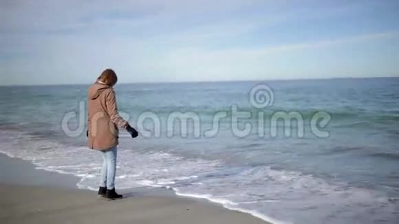 美丽的女人在阳光明媚的海滩上散步视频的预览图