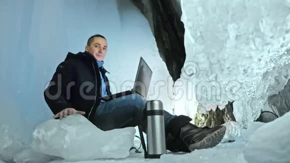 人们坐在冰洞里的笔记本电脑上围绕着神秘美丽的冰窟用户在视频的预览图