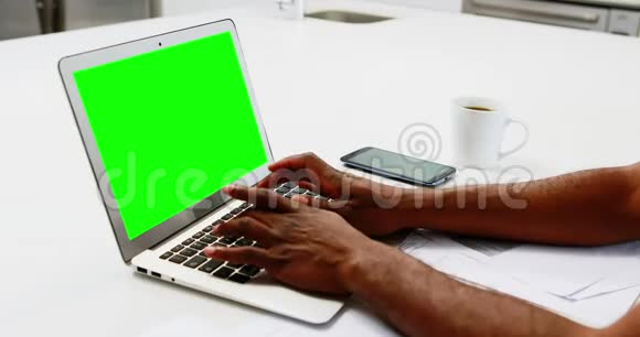 男人在厨房里用笔记本电脑视频的预览图