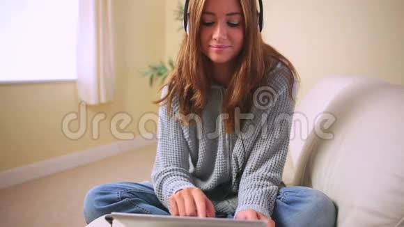 开朗迷人的黑发女人坐在沙发上听音乐视频的预览图