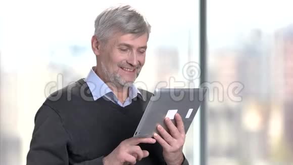 微笑成熟的人使用数字平板电脑视频的预览图