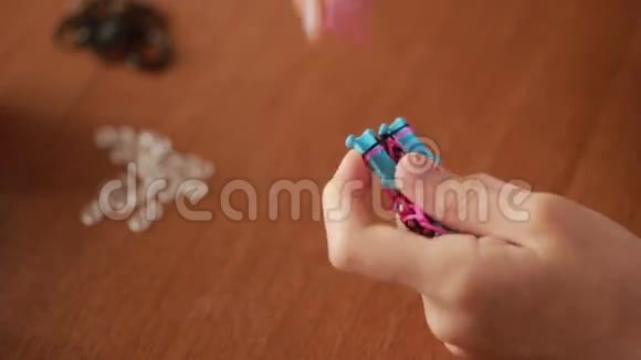 小女孩编织橡皮筋的腕带编织的彩色橡皮筋视频的预览图