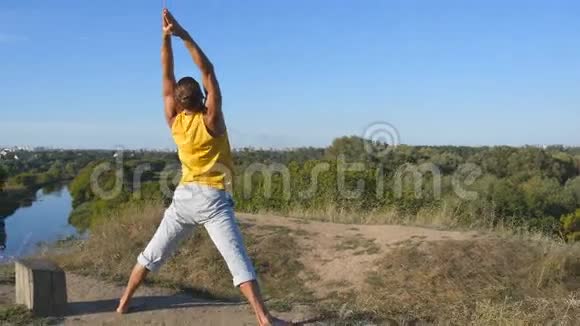 年轻男子站在瑜伽姿势的自然在户外练习瑜伽动作和姿势的人做体力活的运动员视频的预览图