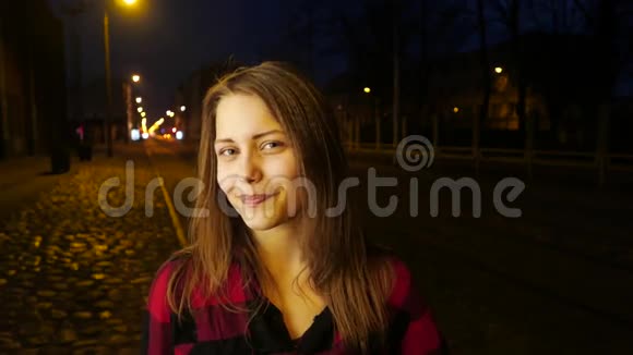一个可爱的沉思微笑的少女在夜城街的肖像视频的预览图