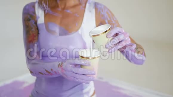 穿紫色颜料的女人坐在油画布上视频的预览图