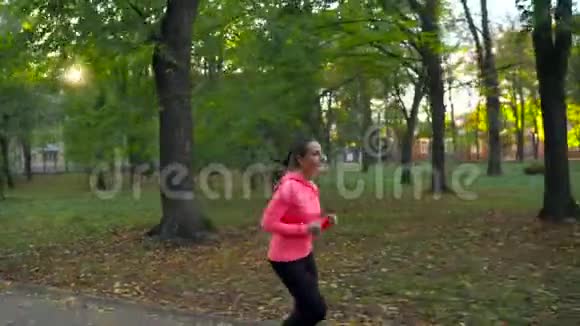 日落时分一个女人在秋天的公园里奔跑视频的预览图