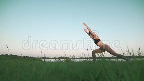 做瑜伽的女人年轻的女孩在蓝色瑜伽垫上安静的风景视频的预览图