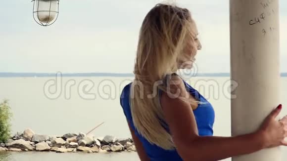 美丽的金发女郎欣赏着大海的地平线在阳台上散步跳舞视频的预览图