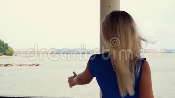 美丽的金发女郎欣赏着大海的地平线在阳台上散步跳舞视频的预览图