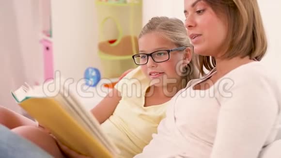 快乐的女孩和妈妈在家看书视频的预览图