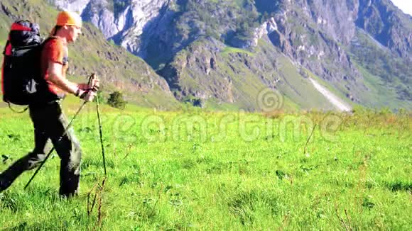 徒步旅行者带着背包在绿色的山地草地上行走夏季运动和娱乐理念视频的预览图