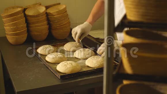 面包师为面包在面团上手工切开面包的制造面包店视频的预览图