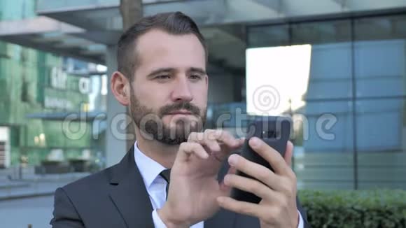 胡子商人使用智能手机在线浏览视频的预览图