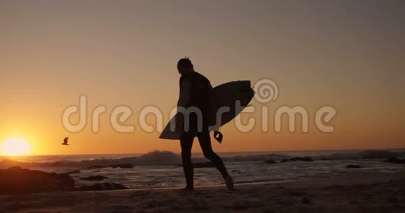 带着冲浪板在海滩散步的人视频的预览图