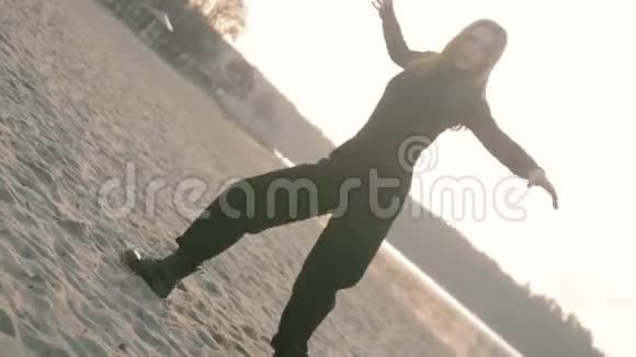 年轻漂亮的女孩穿着黑色衣服跳舞在河畔俯视风景视频的预览图