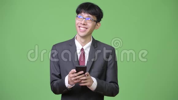 年轻快乐的亚洲商人用电话思考视频的预览图