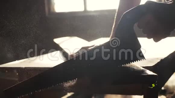人木匠手工制作和工艺概念慢动作视频木工在车间里锯树从一个车间里锯阳光视频的预览图