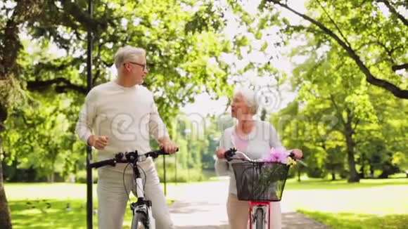 快乐的老年夫妇骑自行车在夏季公园视频的预览图