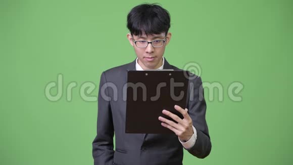 年轻的亚洲商人用剪贴板阅读和思考视频的预览图