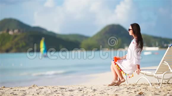 年轻女子在白色海滩上喝着美味的鸡尾酒视频的预览图