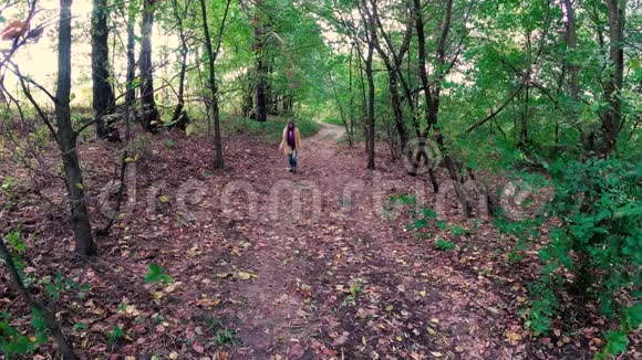 女孩走在秋天五彩缤纷的美丽森林里视频的预览图