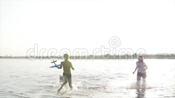 快乐而无忧无虑的童年孩子们和一只狗玩沿着沙子跑笑在河上玩推出一个玩具视频的预览图