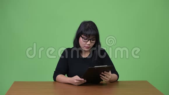 美丽的亚洲女商人阅读剪贴板视频的预览图