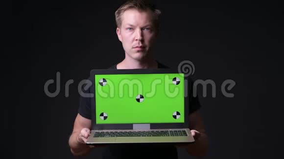年轻的帅哥用带绿色屏幕色键的笔记本电脑视频的预览图