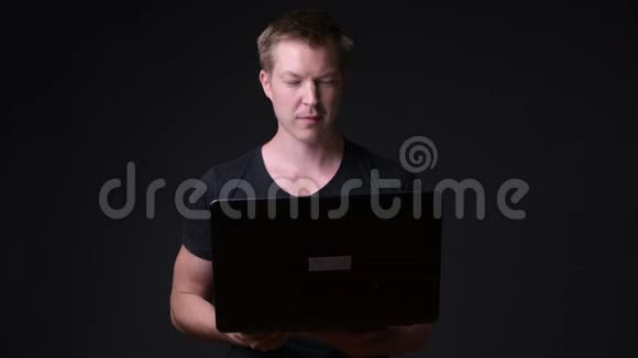 年轻英俊的黑色背景笔记本电脑视频的预览图