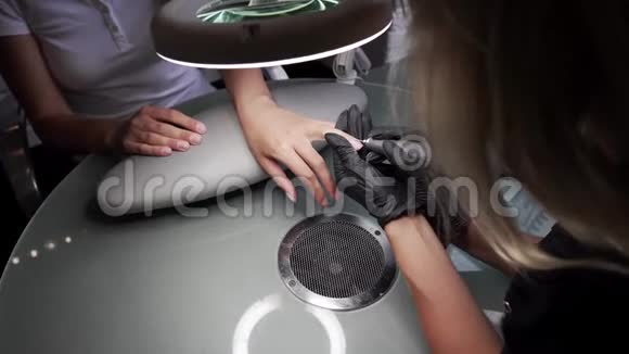 专业硬件修脚使用电机美甲师在美甲沙龙里给女孩磨指甲视频的预览图