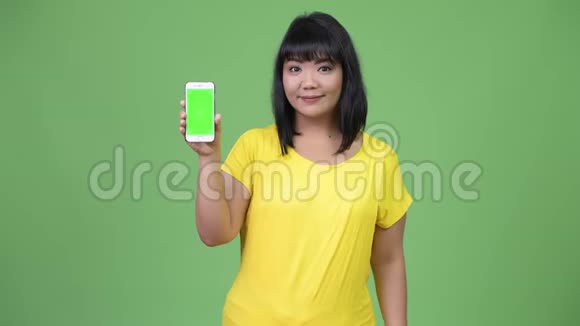 美丽快乐的亚洲女人展示电话视频的预览图