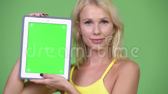 年轻快乐的金发女郎展示数码平板电脑视频的预览图