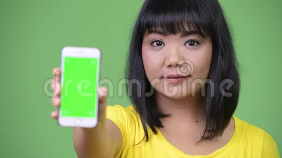 美丽快乐的亚洲女人展示电话视频的预览图