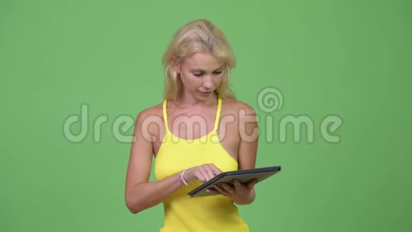 年轻快乐的金发美女使用数码平板电脑视频的预览图